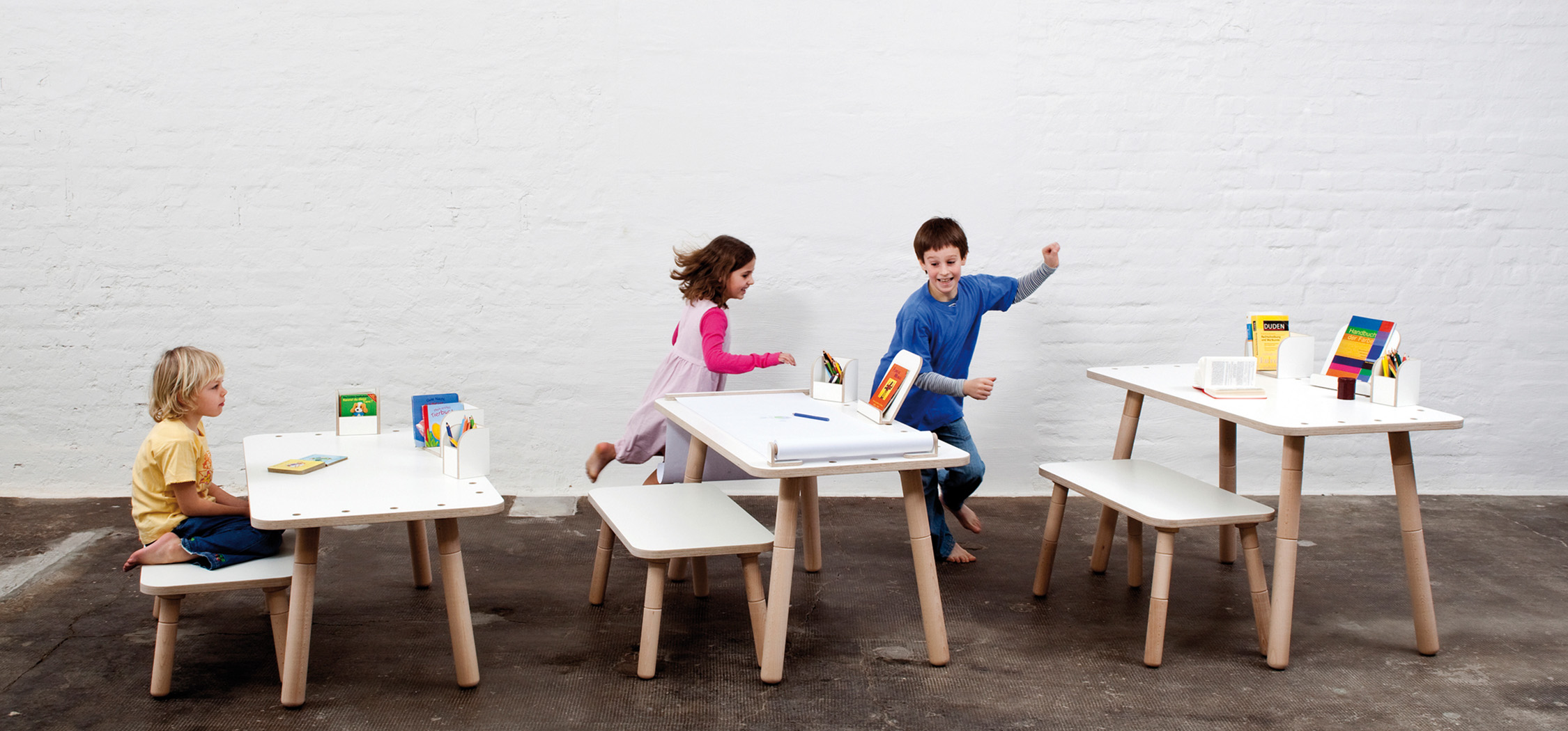 Drei verschiedene Beispiele der Höhenverstellung beim growing table mit spielenden Kindern im Hintergrund