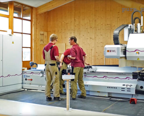 Drei Mitarbeiter von der IWL stehen vor einer Produktionsmaschine in der Produktion
