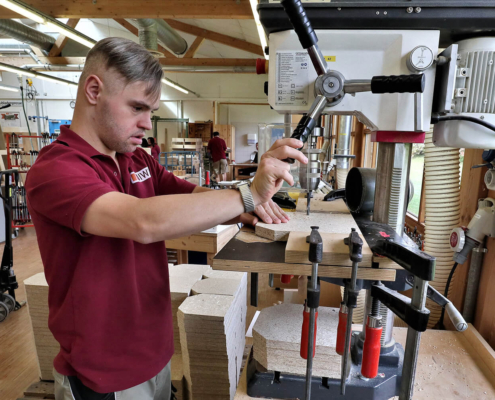 Mitarbeiter von pure position beim Bohren in ein kleines Holzbrett