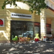 Außenansicht vom Kindermöbelhaus Klein-Holz Laden mit einem Tisch und Stühle für Kinder als Ausstellungsstück am Tag mit Sonnenschein